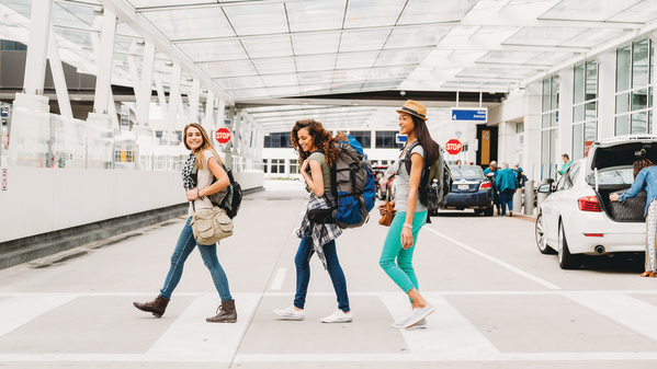three women smiling after getting baggage and walking out of airport