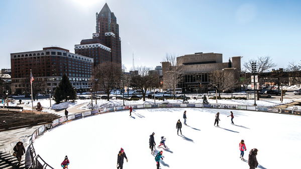 ice skaters at Red Arrow Park with city behind