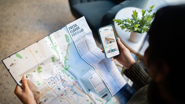 A person holding an official visitors map of Milwaukee with a Map King App open.