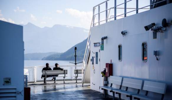 Two passengers sit on the top deck of the ferry