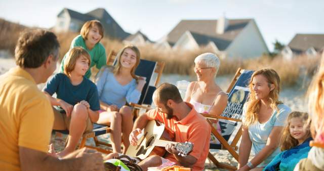 Friends having an oceanfront picnic with beach houses in the background.