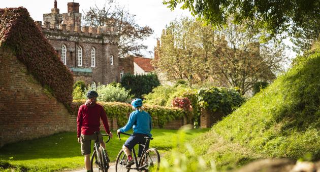 A couple resting from cycling outside a large house in the countryside