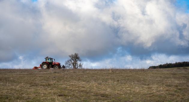 A tractor in an open field under a blue sky