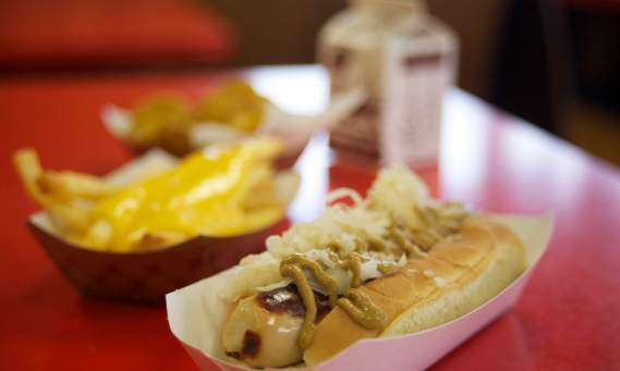 a hofmann's hotdog on a red table with fries and a chocolate milk carton in the background