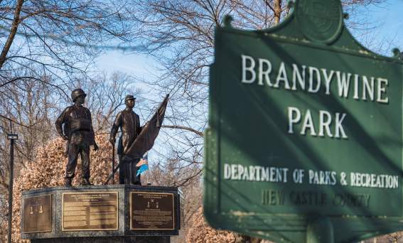 Bronze sculpture of two African American soldiers in the background, with Brandywine Park sign in the foreground