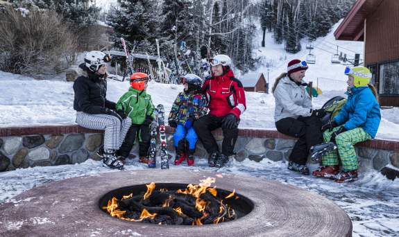 People warming up next to fire pit while on a break from winter activities