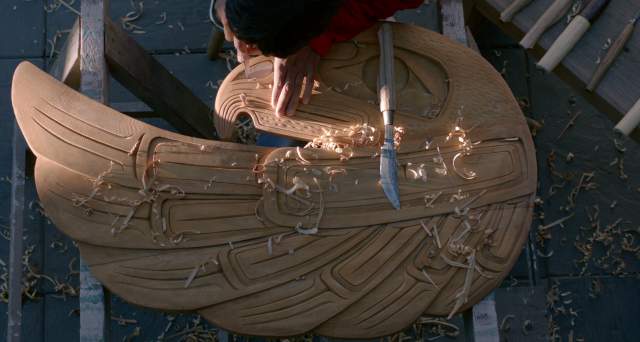 A man uses carving tools to make a work of art.