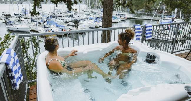 Two women soak in a hot tub overlooking the marina.