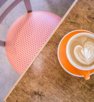A latte on a table at Needmore Coffee Roasters