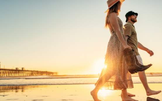 Couple walking Oceanside beach with cowboy boots