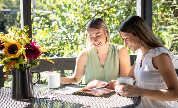 two women sitting at a table drinking coffee and planning their day using our York County Travel Guide