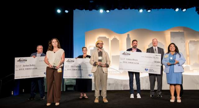Three scholarship recipients standing on a stage in front of three people with giant scholarship checks.