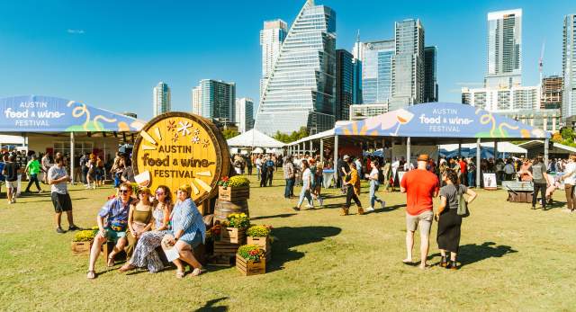 Image of people attending the Austin Food + Wine Festival at Auditorium Shores with the downtown skyline in the background.