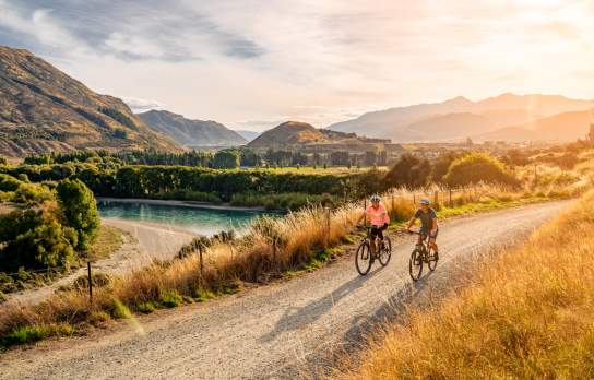 A couple cycle the Twin Rivers Trail in the evening summer light