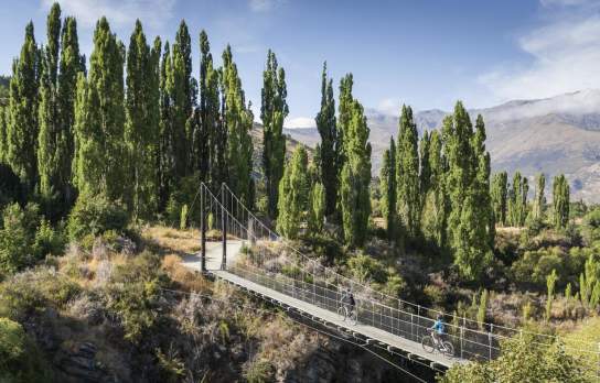 A couple ride on bikes over the Arrow River Bridges Trail