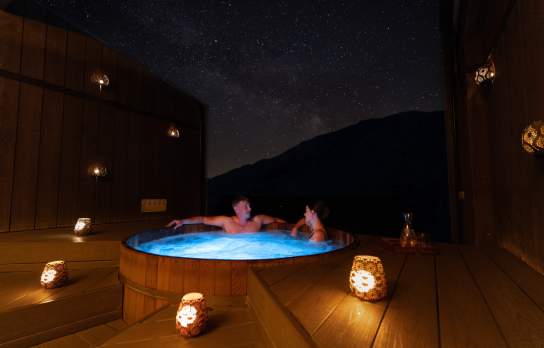 A couple enjoy a private spa at Onsen Hot Pools in Arthurs Point on a clear night
