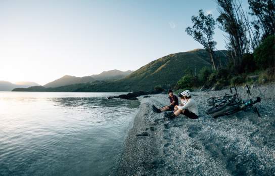 Bike riders sitting by lake at dusk