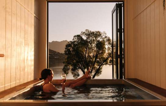 Woman relaxing with a glass of win in a hot tub at Driftaway, Queenstown