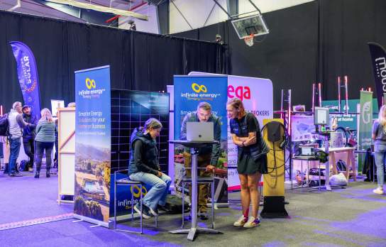 A tradeshow for electric products and prototypes with three people standing around a stand
