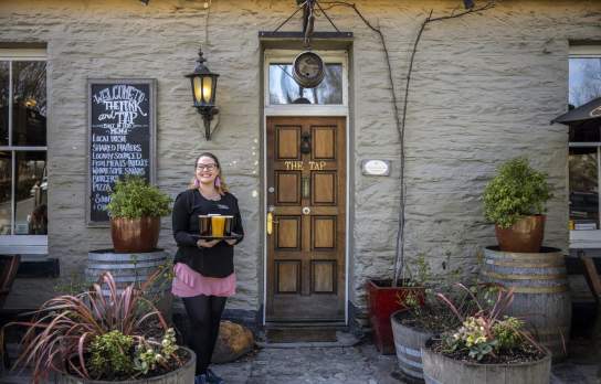 Person with tray of beer standing in front of the Fork and Tap pub Arrowtown