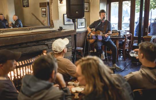Musician playing guitar to people at Pog Mahones Irish Pub