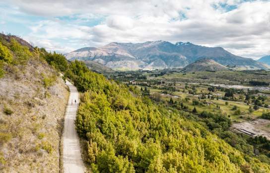 A couple of friends walking up the Tobin's Track in Arrowtown with views of the Whakatipu Basin and The Remarkables