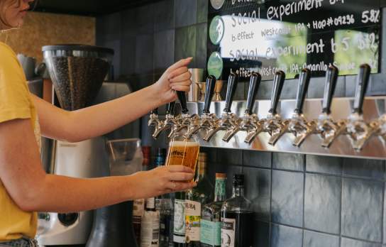 A staff member pouring a brew on tap at b.social Wānaka