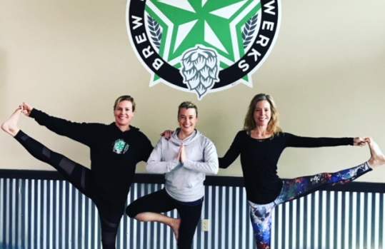 3 women doing yoga poses below a sign for "Brew Republic Bierwerks", the sign is black, white and green