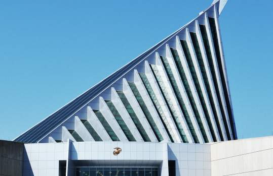 a white building with a large triangle on top of the building, the triangle is apart of the building