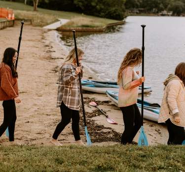 Girls walking into Lake Sara to paddleboard