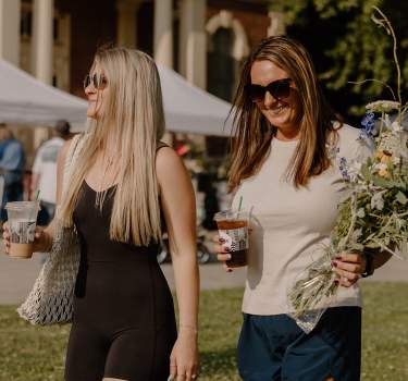 Friends carrying flowers and coffees at the Farmers Market