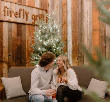 Couple enjoying festive drinks at Firefly Grill on the porch