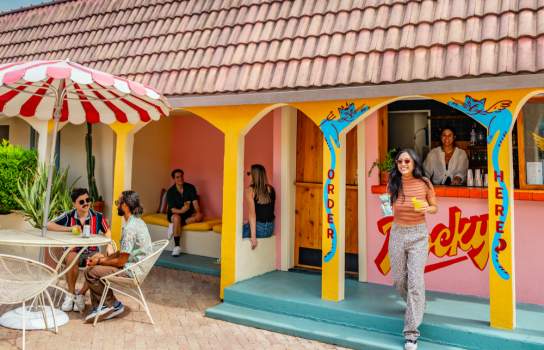 People sitting around an outdoor courtyard with a colorful bar.