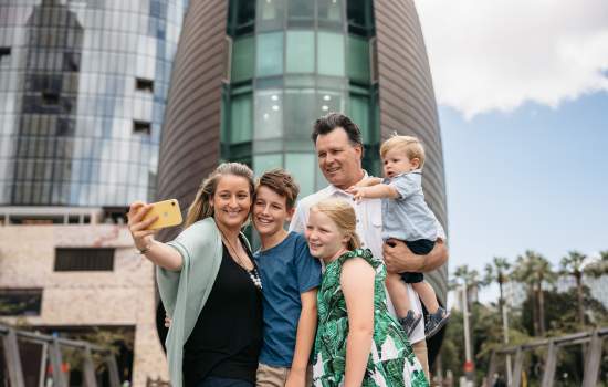 A family pose for a photo in front of The Bell Tower in Perth City