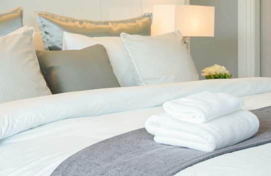 photo of bed with white sheets, and pillows in a cozy, clean room