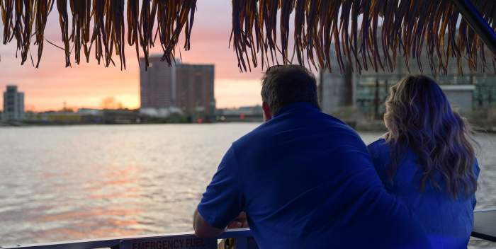 Man and woman looking out over the riverfront at sunset