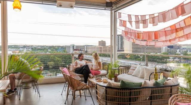 Two people sitting and talking the rooftop restaurant P6 at The LINE Hotel with Lady Bird Lake in the background.