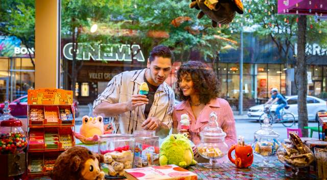 Couple window shopping at a toy store while holding ice cream cones.