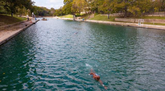 Man freestyle swimming in an empty Barton Springs Pool.