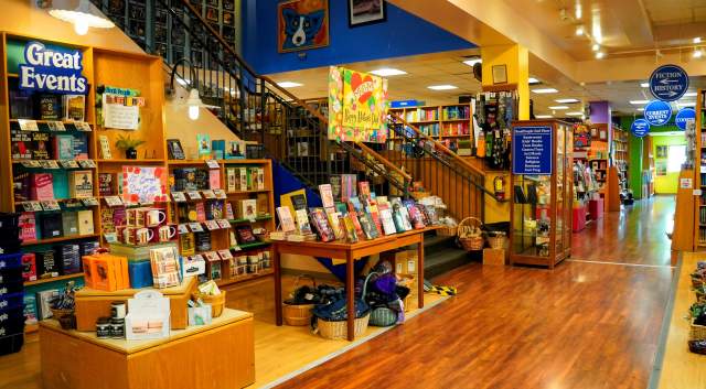 The inside of BookPeople has bookshelves lining the walls and the stairs that lead up to the second floor.