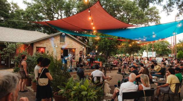 Photo of people sitting on at outdoor patio at Radio Coffee & Beer watching a live band performing on stage.