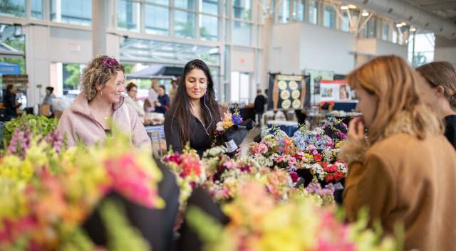 Image of two women browsing the flower selection at the Mueller Farmers Market.