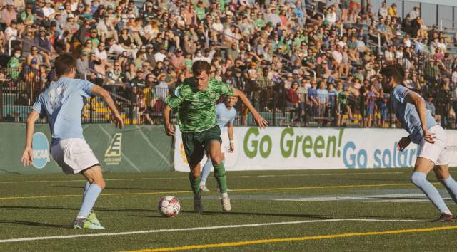 Vermont Green soccer player kicking a ball