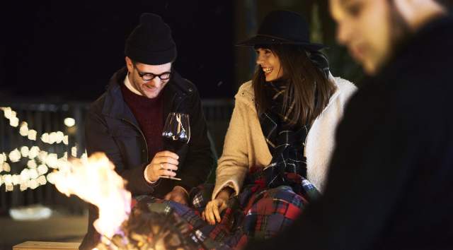 couple shares wine next to a fire pit