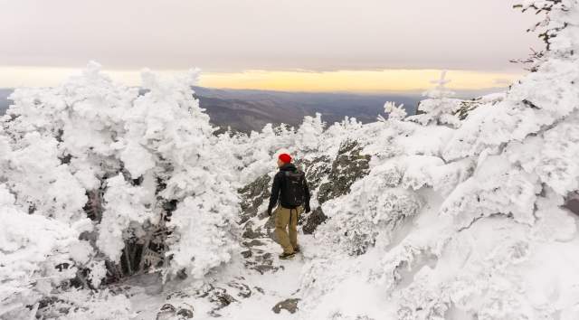 hiker on the top of Mt. Mansfield with snowy trees and icy landscape.