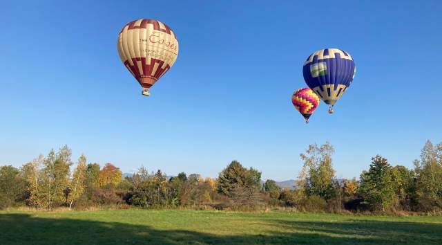 Three hot air balloons take flight in Vermont's countryside.