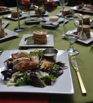Chicken salad on square plates set on a green table cloth with utensils and dessert