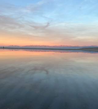 Great Salt Lake at sunset with the mountains a light pink and the sunset and sky reflected in the lake