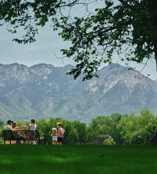 Family picnic in a park with lush green grass in and a scenic mountain view