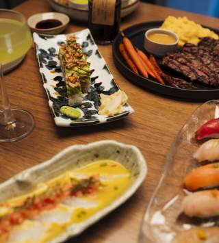 Plates of sushi and a steak with drinks
